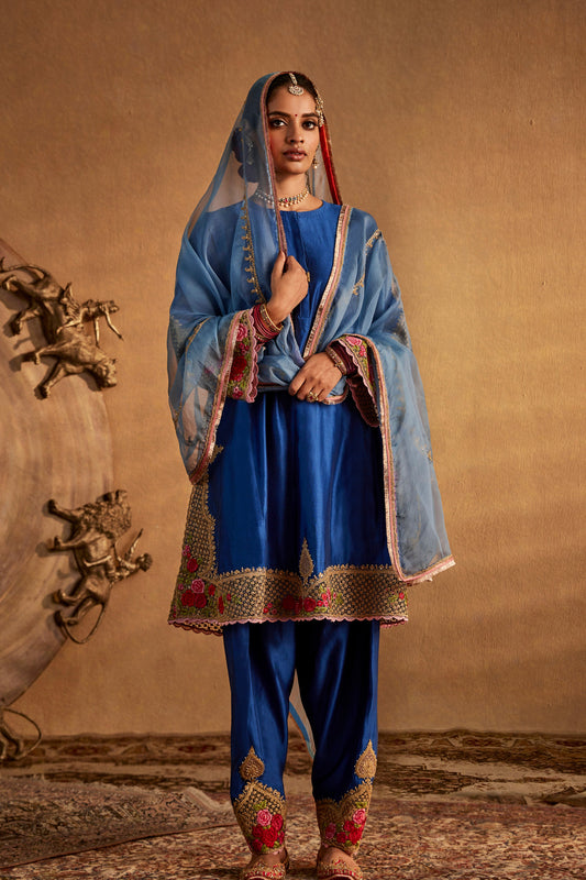 Model in a dark blue silk kurta set with ornate floral embroidery, traditional South Asian dress, stylish everyday wear.