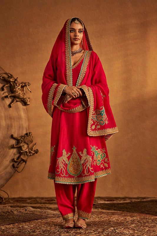 Woman in Rani Pink Kurta Set with embroidered hem, traditional South Asian formal outfit.