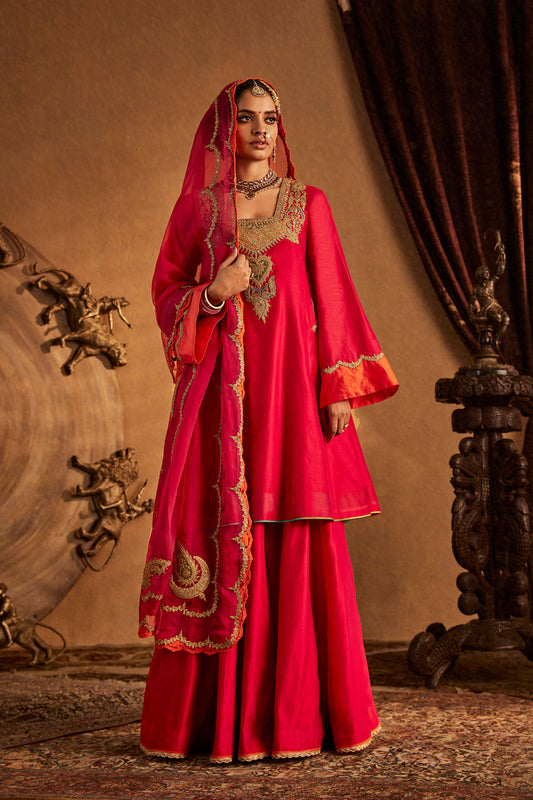Woman in Rani Pink Sharara Set with orange trim, festive South Asian ethnic outfit, full length.
