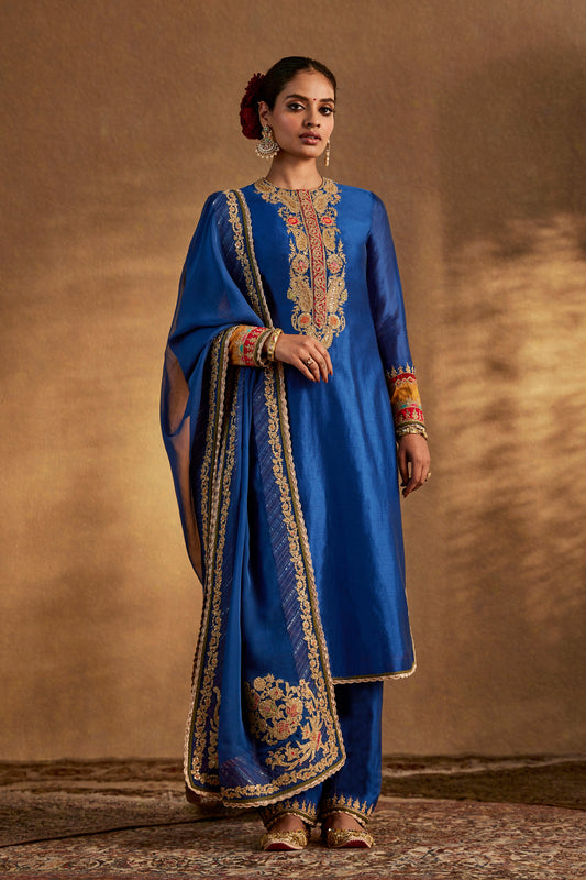 Model in a deep blue floral kurta set, intricate embroidery, traditional South Asian fashion, formal ethnic attire.