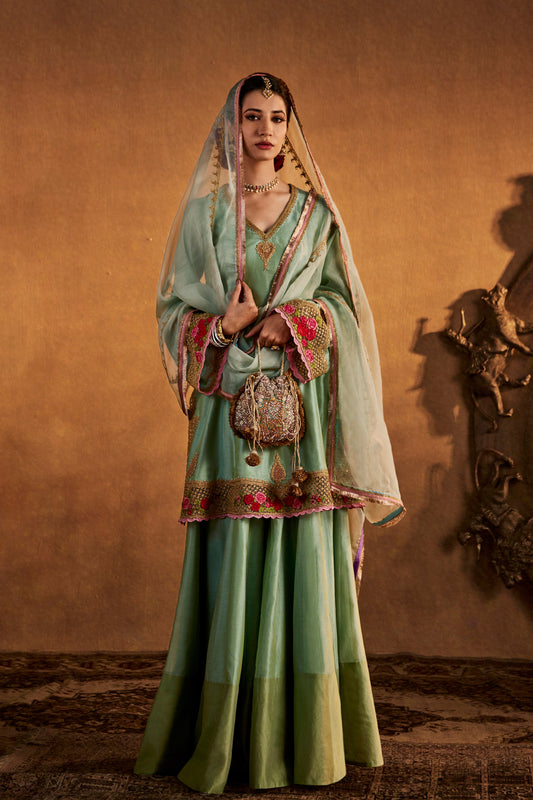 Woman in ice blue embroidered ethnic sharara set, traditional South Asian fashion, full length.