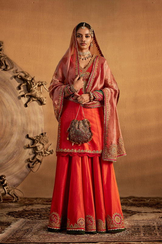 Model in a peach amber sharara set, burnt orange skirt, flowing silhouette, intricate details, cultural attire, festive.