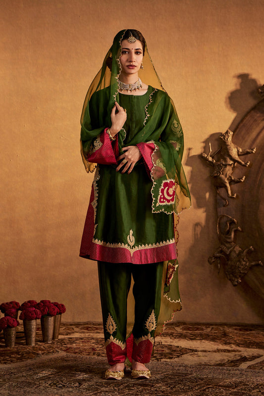 Woman in deep green kurta set with pink accents, casual South Asian ethnic wear, full length.