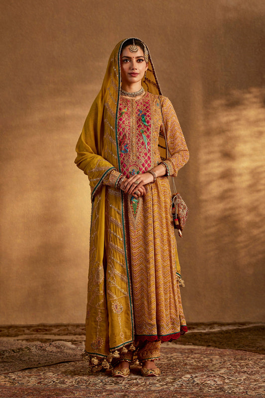 Woman in a rich mustard yellow traditional South Asian dress with colorful embroidery, elegant draping, cultural attire.