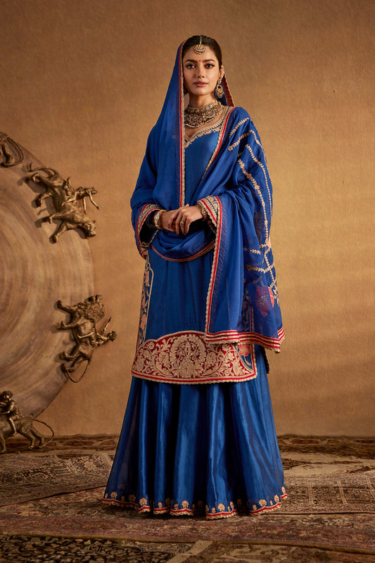 Model in a dark blue floral sharara set, elegant embroidery, traditional South Asian formal attire, festive occasion wear.