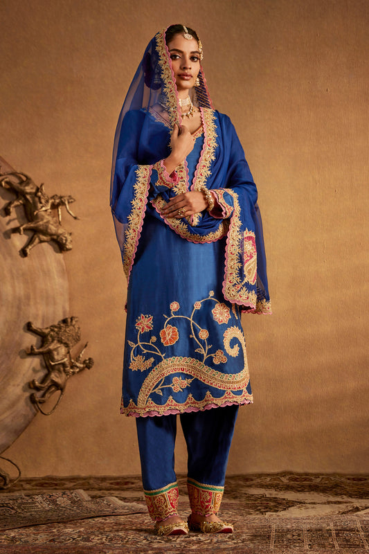 Model in a deep blue floral kurta set, intricate embroidery, traditional South Asian fashion, formal ethnic attire.