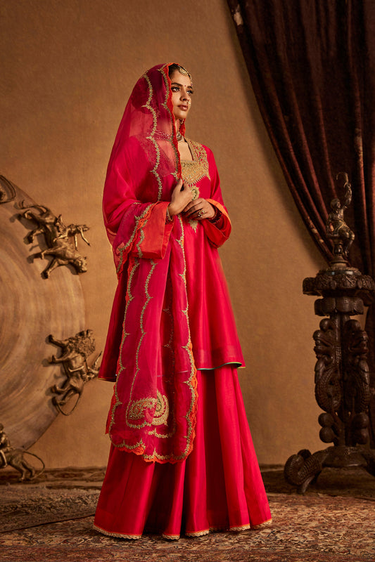 Woman in Rani Pink Sharara Set with orange trim, festive South Asian ethnic outfit, full length.