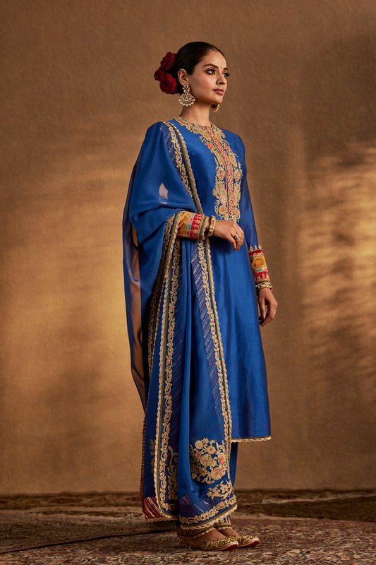 Model in a deep blue floral kurta set, intricate embroidery, traditional South Asian fashion, formal ethnic attire.