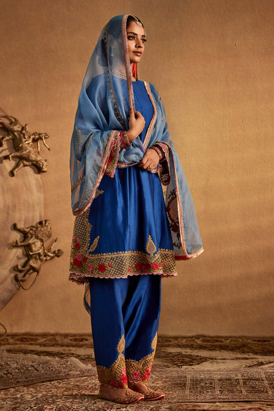 Model in a dark blue silk kurta set with ornate floral embroidery, traditional South Asian dress, stylish everyday wear.