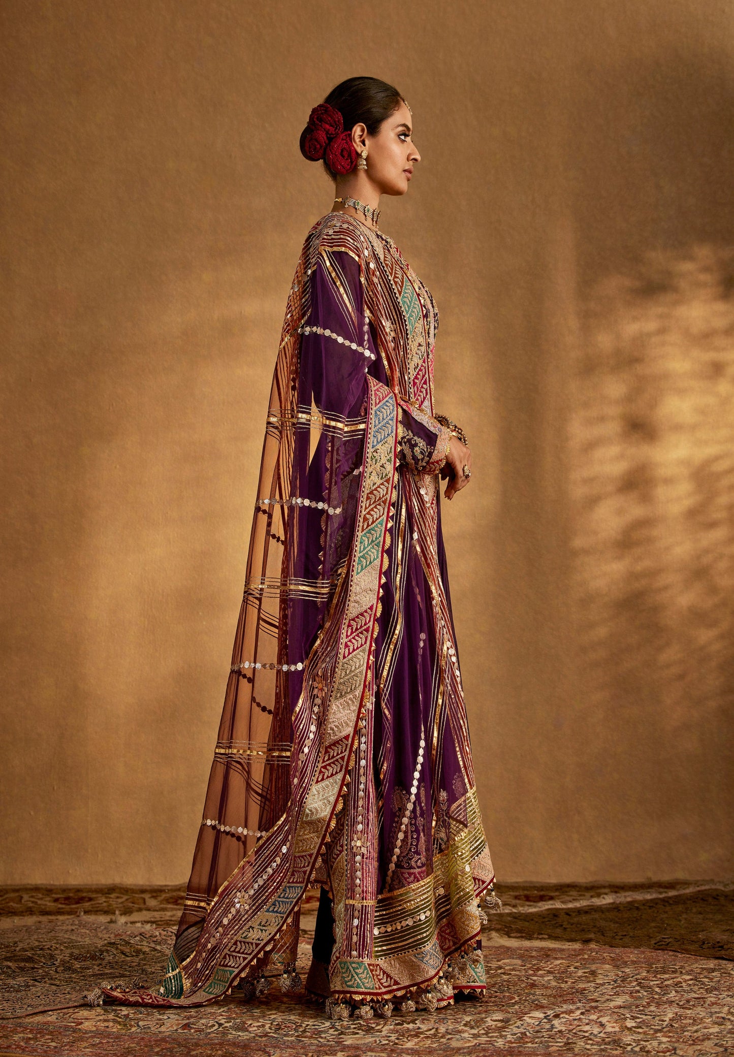 Stunning purple designer anarkali suit with intricate gold embroidery, matching dupatta, and traditional jewelry for weddings.