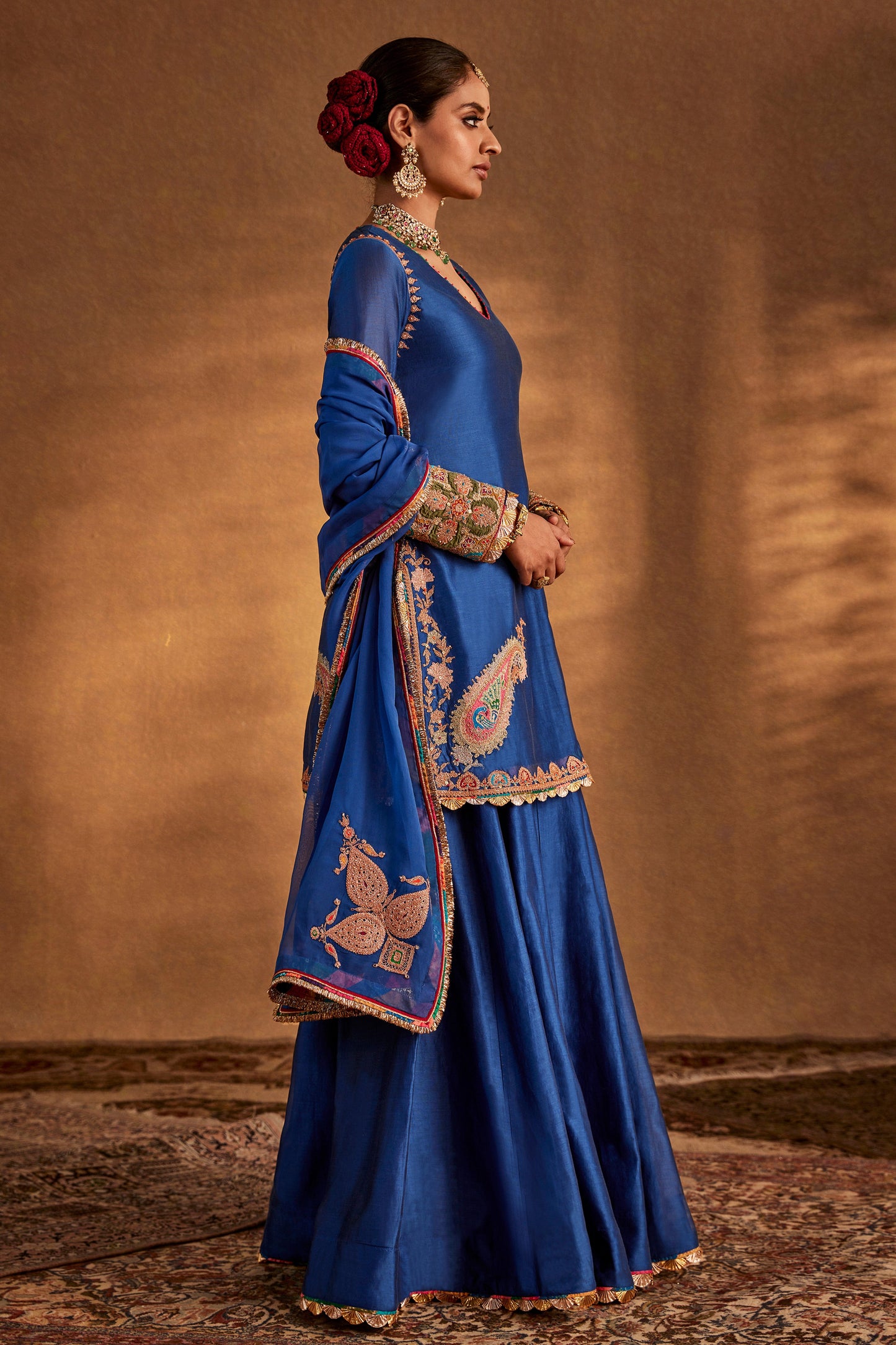 Model in a deep blue sharara set with peacock embroidery, flowing skirt, traditional South Asian formal dress, stunning.