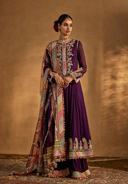 Stunning purple designer anarkali suit with intricate gold embroidery, matching dupatta, and traditional jewelry for weddings.