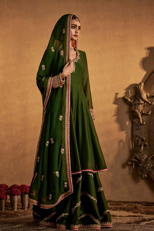 Model in a juniper green sharara set, subtle embroidery, traditional South Asian dress, stylish formal ethnic wear.